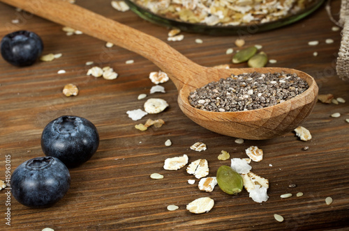 Wooden spoon of chia seeds with blueberries and oatmeal flakes on a wooden background. Superfood and healthy eating concept.