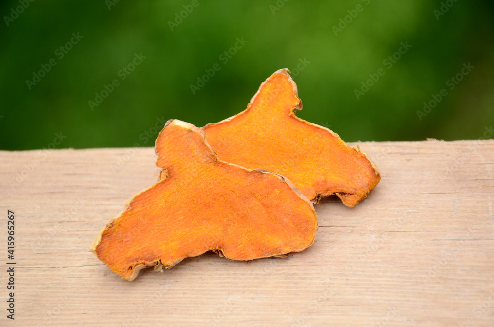 the slice brown orange ripe turmeric on the green brown wooden background. the slice brown orange ripe turmeric on the green brown wooden background.