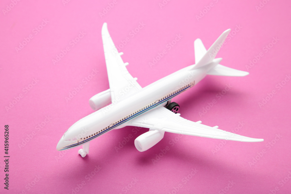 Model airplane on pink pastel color background.