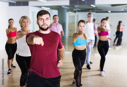 Happy people of different ages training sport dance elements in dancing hall