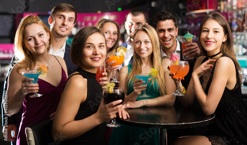 Portrait of young females and males celebrating corporate in the bar at night