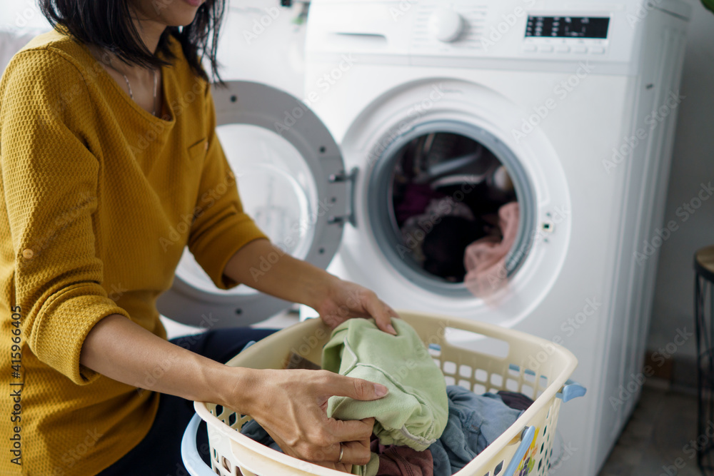 close up of woman in front of the washing machine doing some laundry loading clothes inside close up of woman in front of the washing machine doing some laundry loading clothes inside