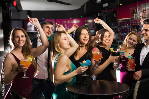 Joyful colleagues dancing on corporate party with alcohol in hands