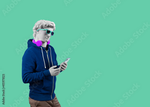 Modern art collage. Concept portrait of a man  holding mobile smartphone using app texting sms message. Gypsum head of of David.