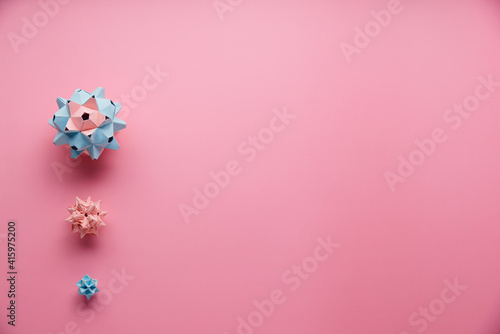 Set of multicolor handmade modular origami balls or Kusudama Isolated on pink background. Visual art, geometry, art of paper folding, paper crafts. Top view, close up, selective focus, copy space.
