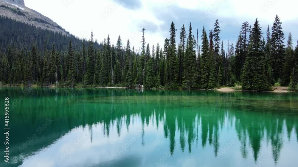 Orbital view of turquoise clear water surrounded by green forest mountain and blue skies in background Orbital view of turquoise clear water surrounded by green forest mountain and blue skies in background