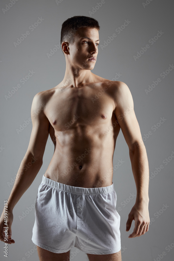 male bodybuilder in shorts gesturing with his hands on a gray background male bodybuilder in shorts gesturing with his hands on a gray background