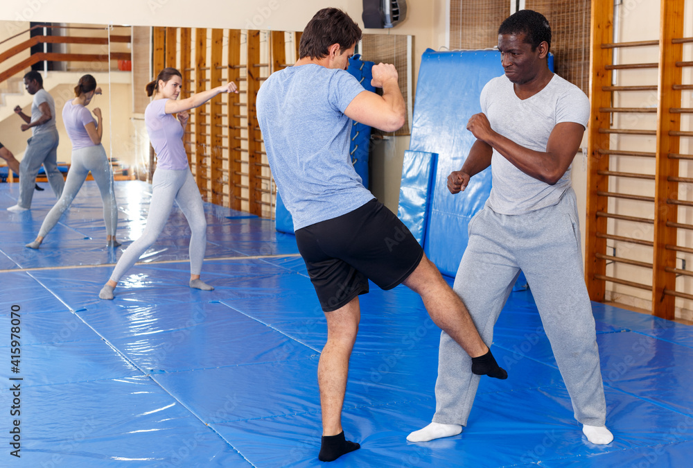 Men practicing effective techniques of self-defence during individual class in training room