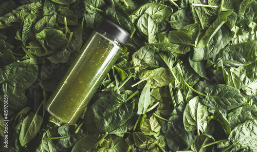 Spinach lettuce salad smoothie. Dark moody green background. Close up of green leaves. Flat lay
