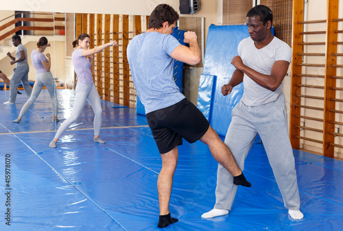 Men practicing effective techniques of self-defence during individual class in training room