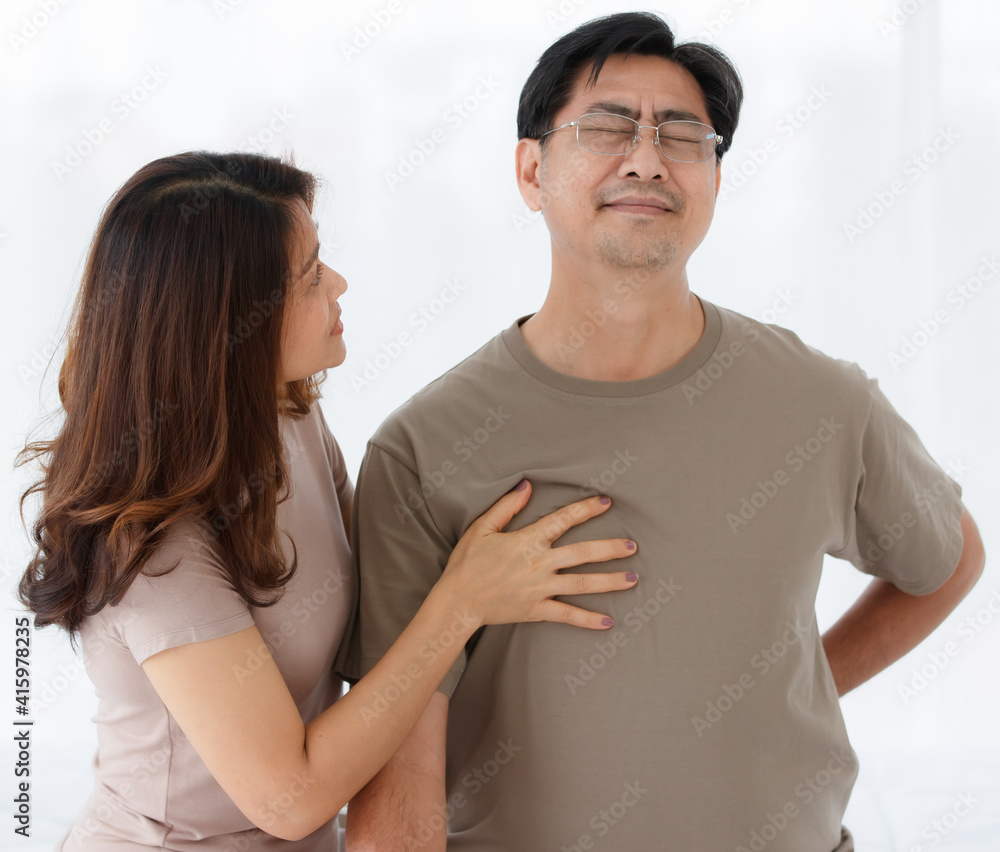 Portrait shot of senior Asian lover couple wearing eyeglasses. Husband suddenly feels uncomfortable from acute back pain with worried wife taking care her husband with isolated white background. Portrait shot of senior Asian lover couple wearing eyeglasses. Husband suddenly feels uncomfortable from acute back pain with worried wife taking care her husband with isolated white background.
