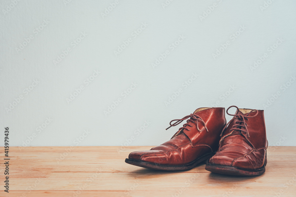 Men's brown shoes on a wooden floor.