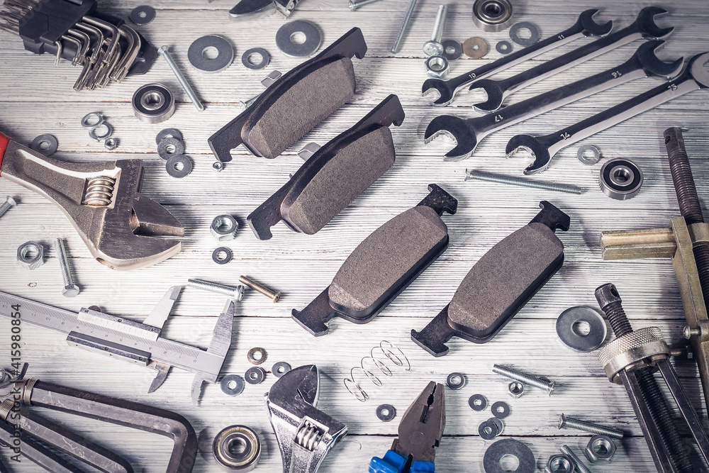 Fototapeta premium New car brake pads on a white wooden background.