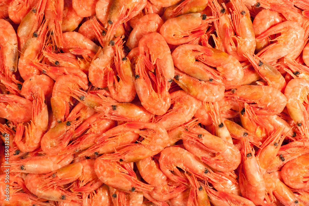 Frozen pink raw shrimp in box top view. Uncooked unpeeled seafood close up background. Fish or food market concept Frozen pink raw shrimp in box top view. Uncooked unpeeled seafood close up background. Fish or food market concept