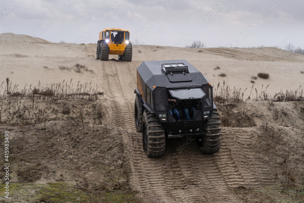 All-terrain vehicles driving through a sandy hilly landscape All-terrain vehicles driving through a sandy hilly landscape