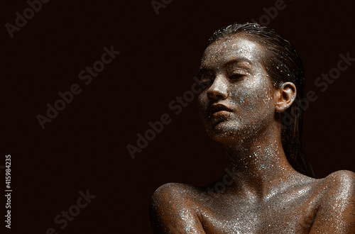 Glittering silver female body art, young beautiful naked girl with wet hair, skin in sparkles, copy space