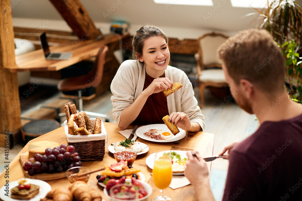 Happy woman enjoying in conversation with her boyfriend during breakfast at dining table. Happy woman enjoying in conversation with her boyfriend during breakfast at dining table.