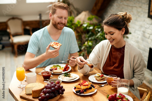 Young couple enjoying while having breakfast together at dining table.