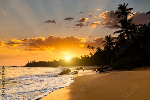 Romantic sunset on a tropical beach with palm trees. Vacation at sea