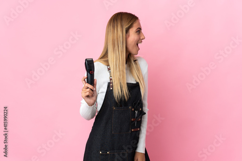 Young hairdresser woman isolated on pink background laughing in lateral position
