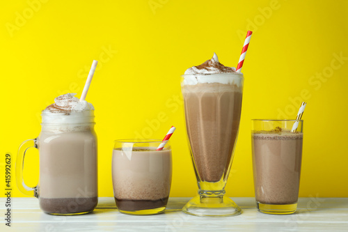 Glasses of chocolate milkshake against yellow background