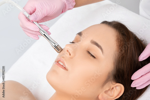 The cosmetologist makes the procedure Microdermabrasion of the face skin of a beautiful girl in a beauty salon.Cosmetology and professional skin care.