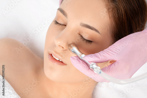 The cosmetologist makes the procedure Microdermabrasion of the face skin of a beautiful girl in a beauty salon.Cosmetology and professional skin care.