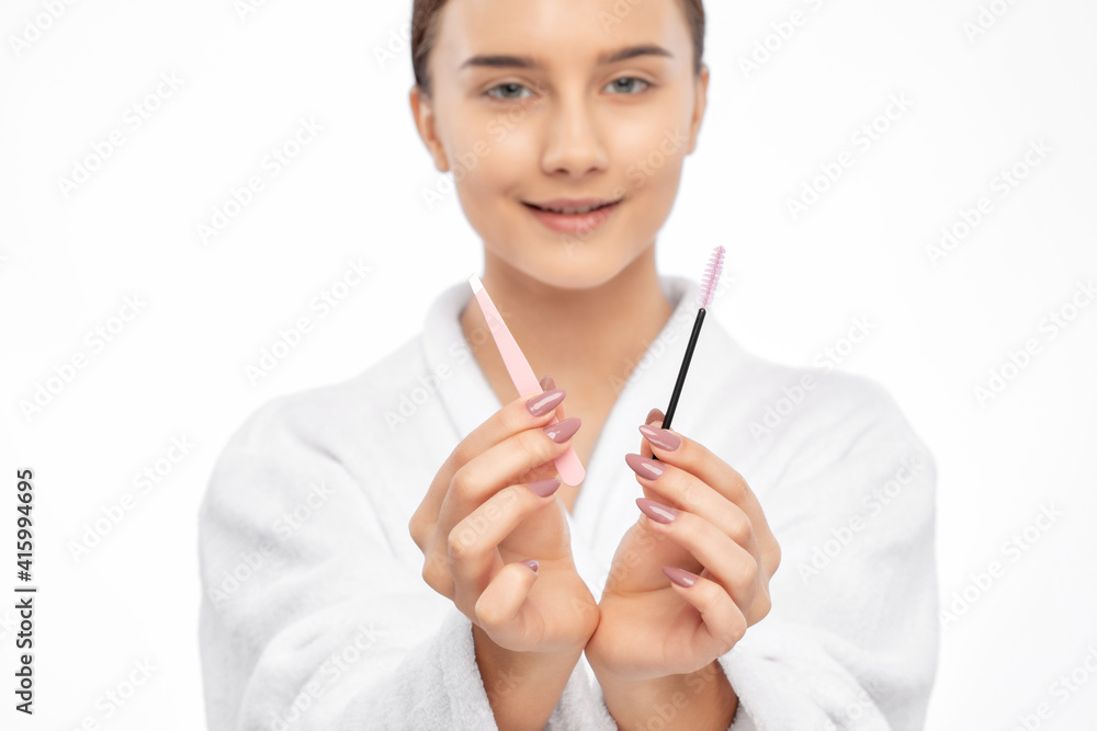 Young attractive woman in a white coat plucking eyebrows. Professional make-up and cosmetic skin care. Young attractive woman in a white coat plucking eyebrows. Professional make-up and cosmetic skin care.