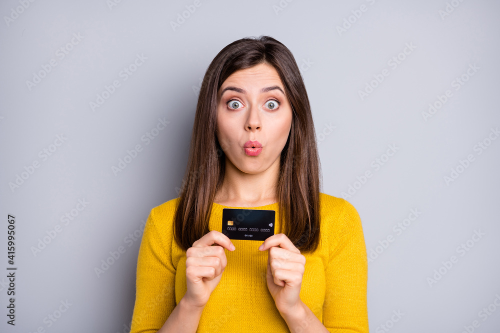 Portrait of attractive amazed funky girl holding in hands bank card pout lips novelty solution isolated over grey color background Portrait of attractive amazed funky girl holding in hands bank card pout lips novelty solution isolated over grey color background