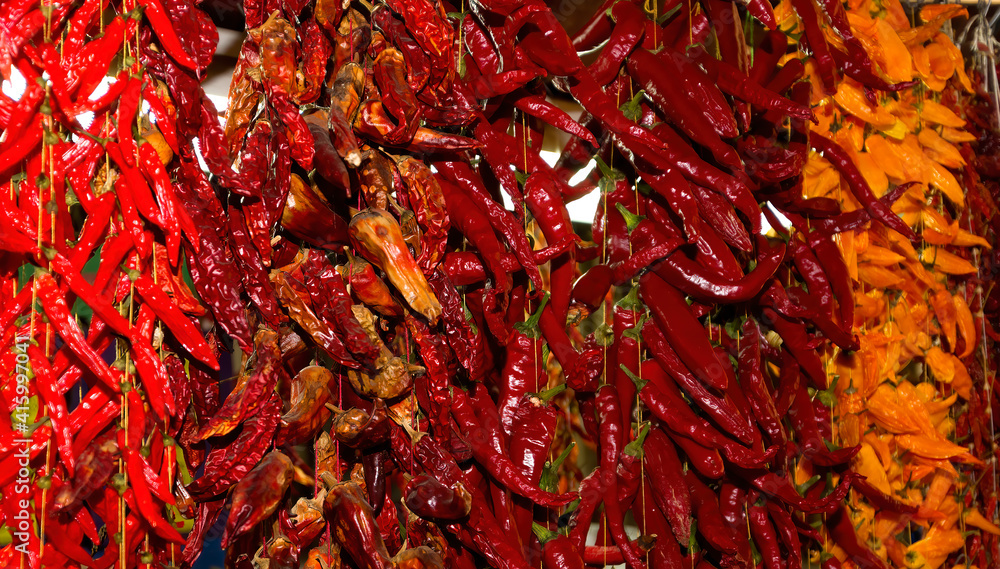 Fototapeta premium Multicolored chili peppers hanging on threads in a Funchal market in Madeira