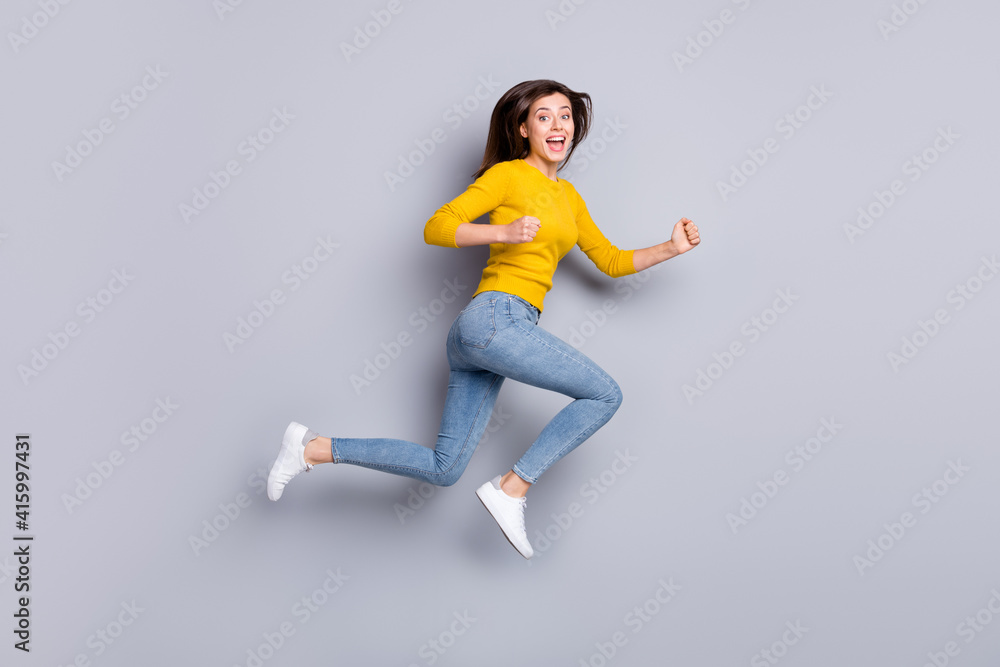 Full size profile photo of hooray brunette nice lady jump run wear yellow sweater jeans sneakers isolated on grey color background