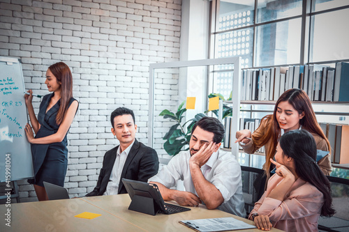 Tired businessman sleeping in a meeting conference in office ,  business team people looking sternly at snoring at meeting photo