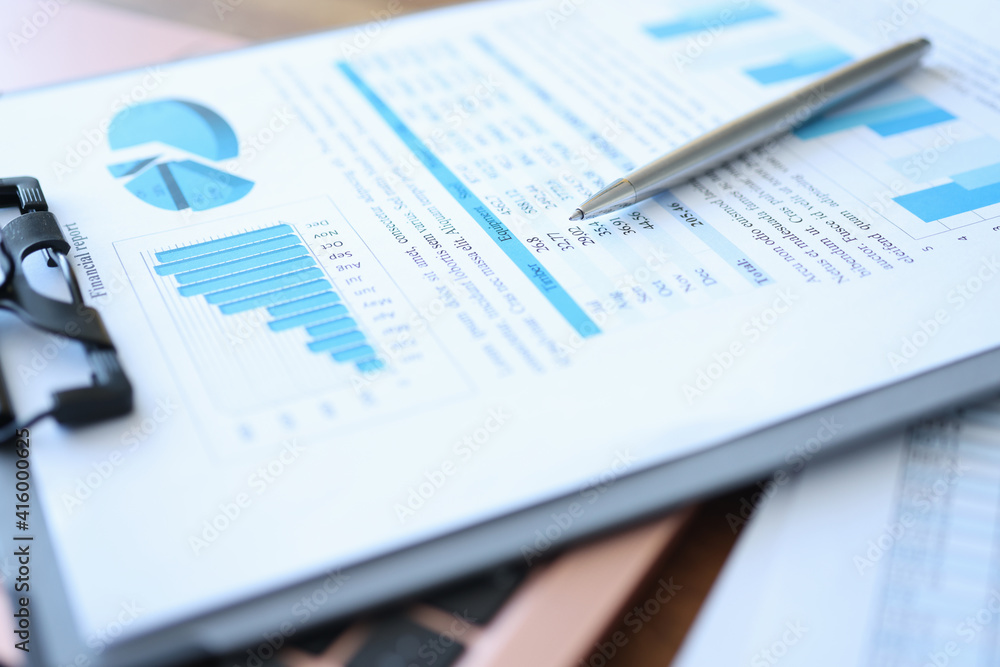 Clipboard with financial report and pen lie on table Clipboard with financial report and pen lie on table