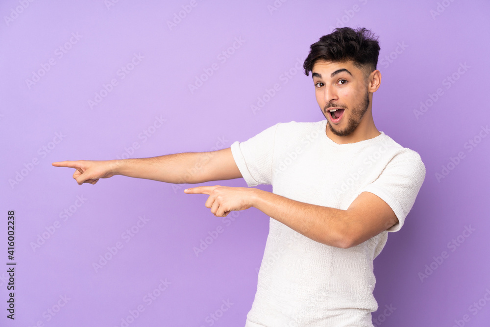 Arabian handsome man over isolated background pointing finger to the side and presenting a product Arabian handsome man over isolated background pointing finger to the side and presenting a product