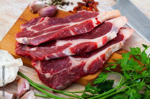 Close up of raw veal on wooden surface with ingredients, nobody