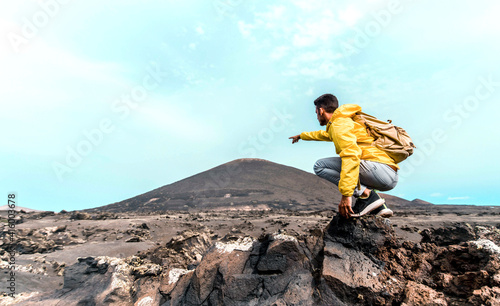 Successful hiker pointing to the mountains - Man with backpack hiking outdoor - Sport and success concept