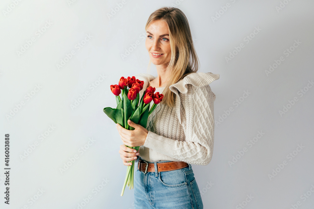 Young caucasian attractive smiling woman with a bouquet of red tulips. Copy space for text. Concept for womens day and mothers day. Young caucasian attractive smiling woman with a bouquet of red tulips. Copy space for text. Concept for womens day and mothers day.