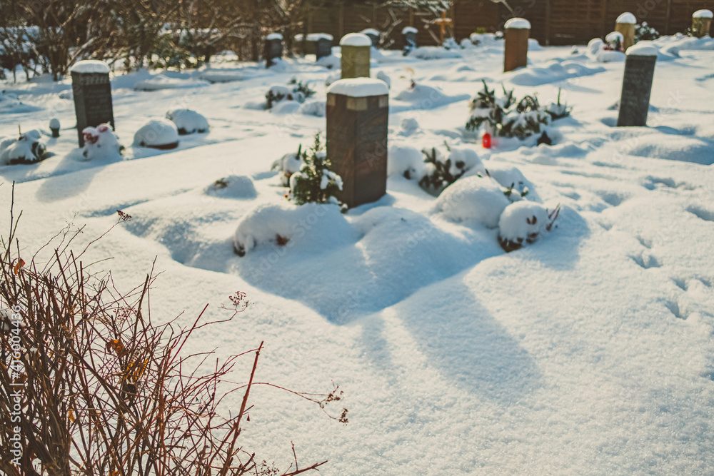 Obraz premium Urnengrab auf Friedhof im Winter bei Schnee Tod und Ewigkeit