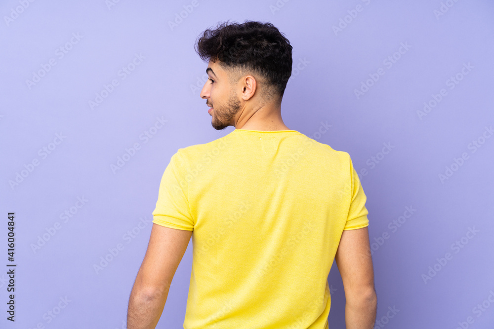 Arabian handsome man over isolated background in back position and looking side Arabian handsome man over isolated background in back position and looking side
