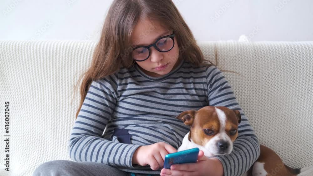 4k. little cute caucasian girl in glasses study in phone with dog 4k. little cute caucasian girl in glasses study in phone with dog