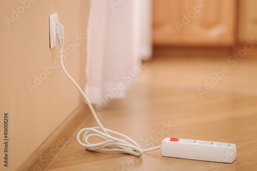 White extension into power outlet indoors. Photo of empty extension cord at home
