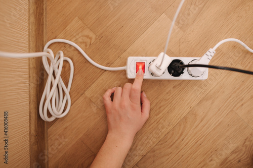 Bilde på lerret Top view of female hand turn on the extension cord at home