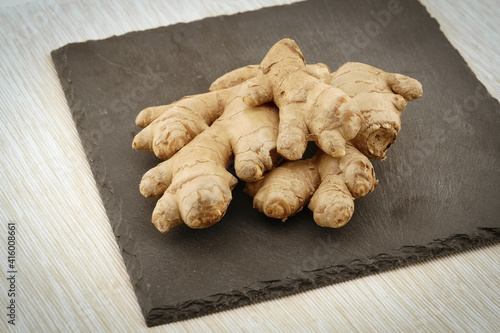 ginger roots on black slate plate. fabric tablecloth on table