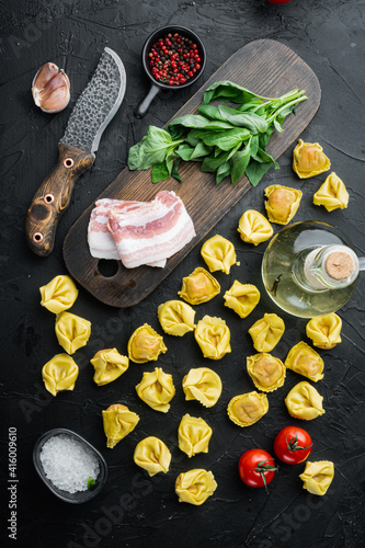 Raw homemade Tortellini with cured ham, on black background, top view flat lay