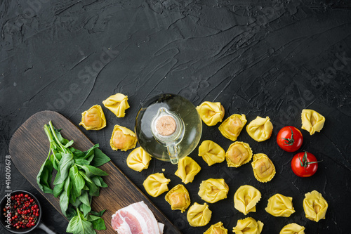 Raw homemade Tortellini with cured ham, on black background, top view flat lay,  with copy space for text
