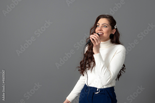 attractive female conference speaker during presentation, holds microphone and makes some gestures