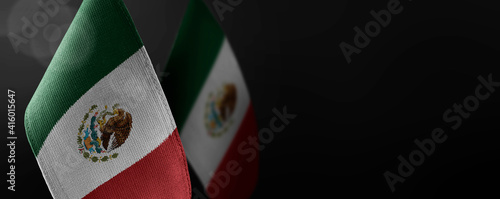 Small national flags of the Mexico on a dark background photo