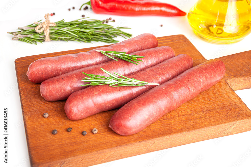 Raw meat beef sausages for grill and spicy, herbs rosemary, pepper, salt on table Raw meat beef sausages for grill and spicy, herbs rosemary, pepper, salt on table