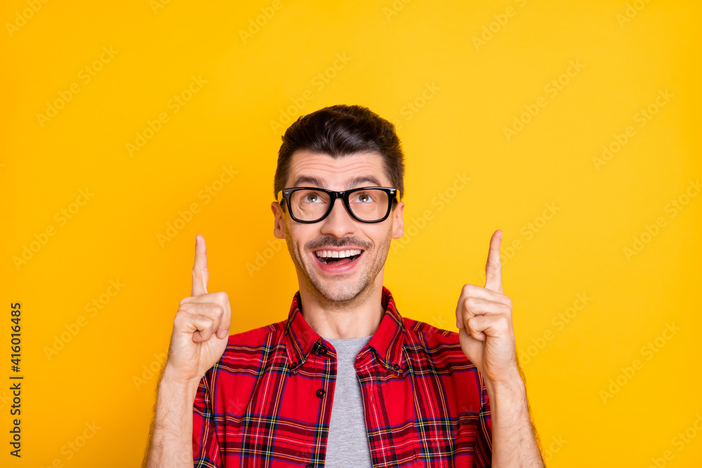 Photo of happy excited man point look index fingers information empty space above isolated on yellow color background
