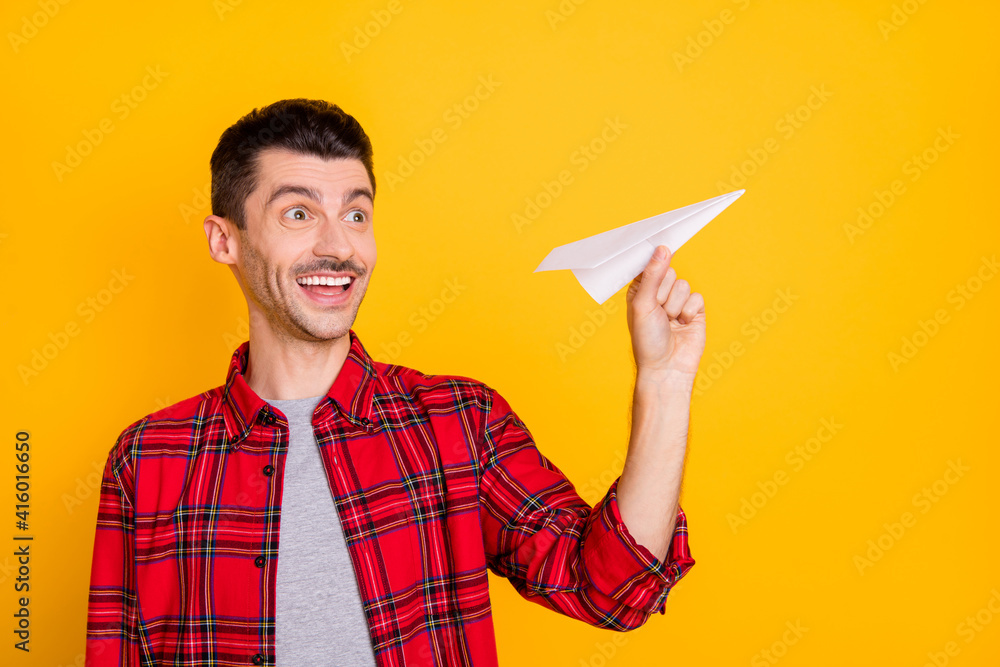 Photo of charming funny young guy dressed red plaid shirt throwing paper plane empty space isolated yellow color background Photo of charming funny young guy dressed red plaid shirt throwing paper plane empty space isolated yellow color background